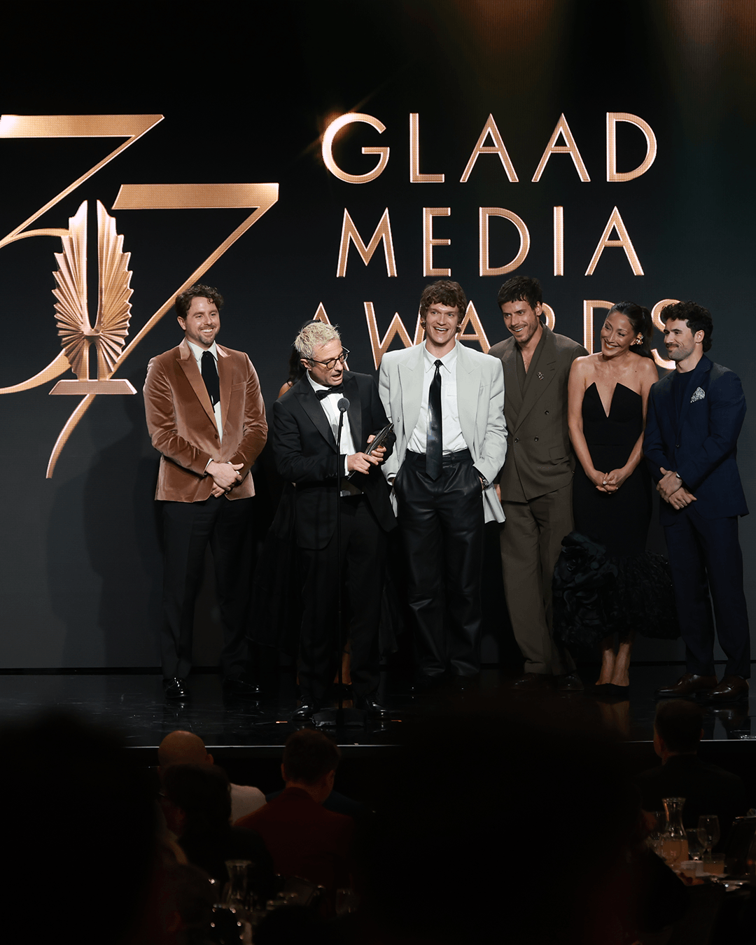 A group on stage in front of the 37th GLAAD Media Awards logo.