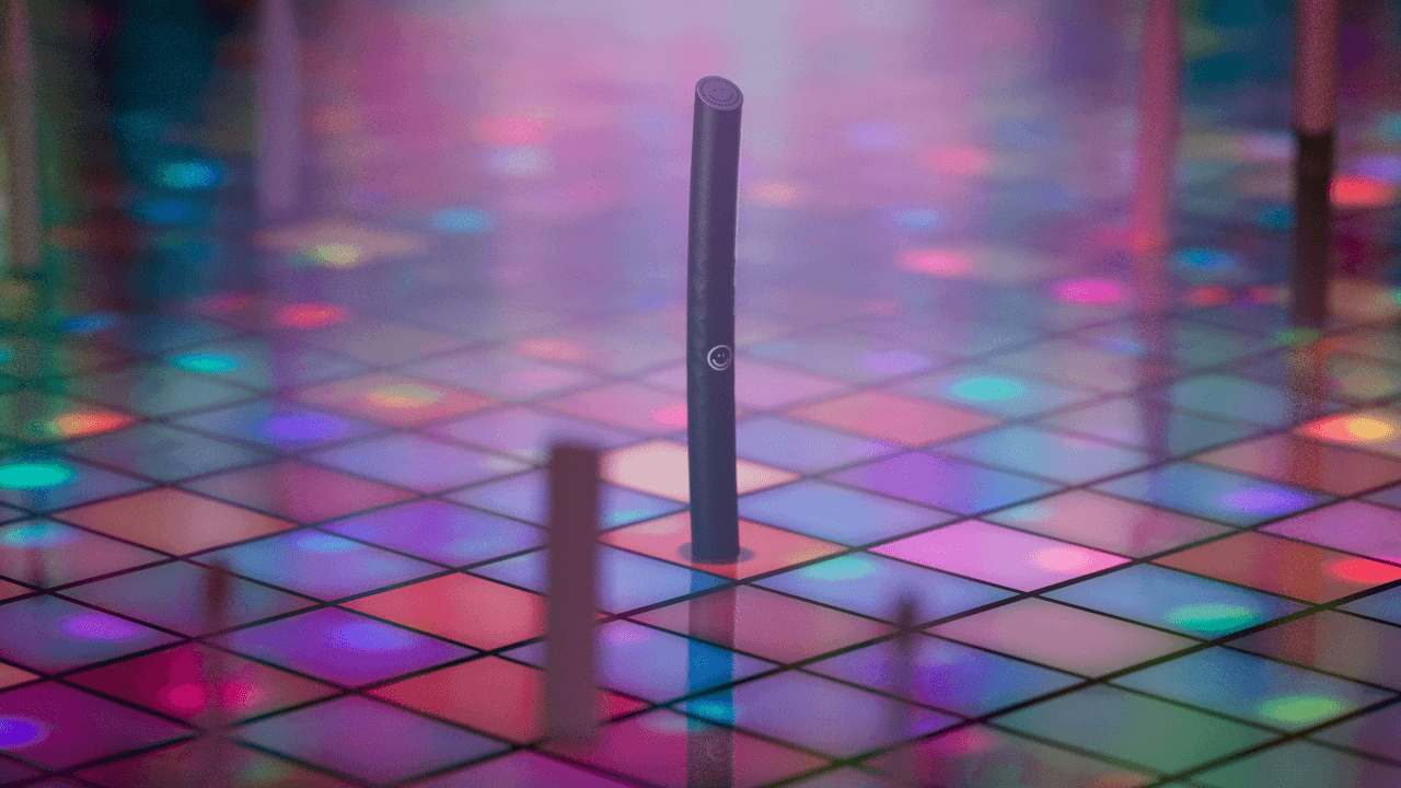 A pink Burst Curve toothbrush stands on a colorful illuminated dance floor.