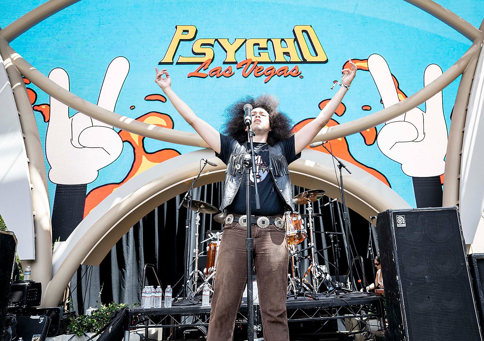 A performer stands before illustrated Psycho Las Vegas stage visuals.