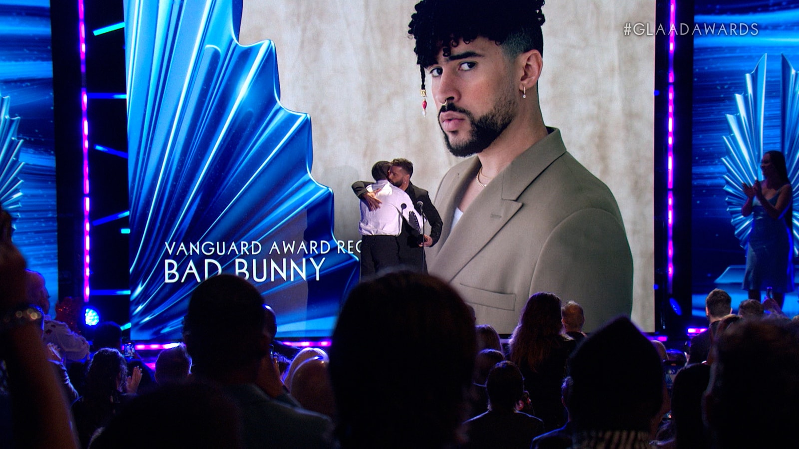 A speaker stands before a Vanguard Award graphic featuring Bad Bunny.