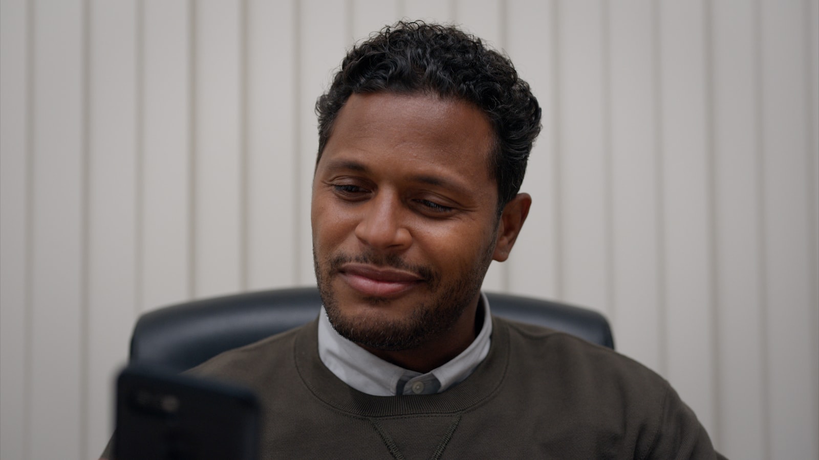 A man in a dark sweater sits at a desk in a ZipRecruiter spot.