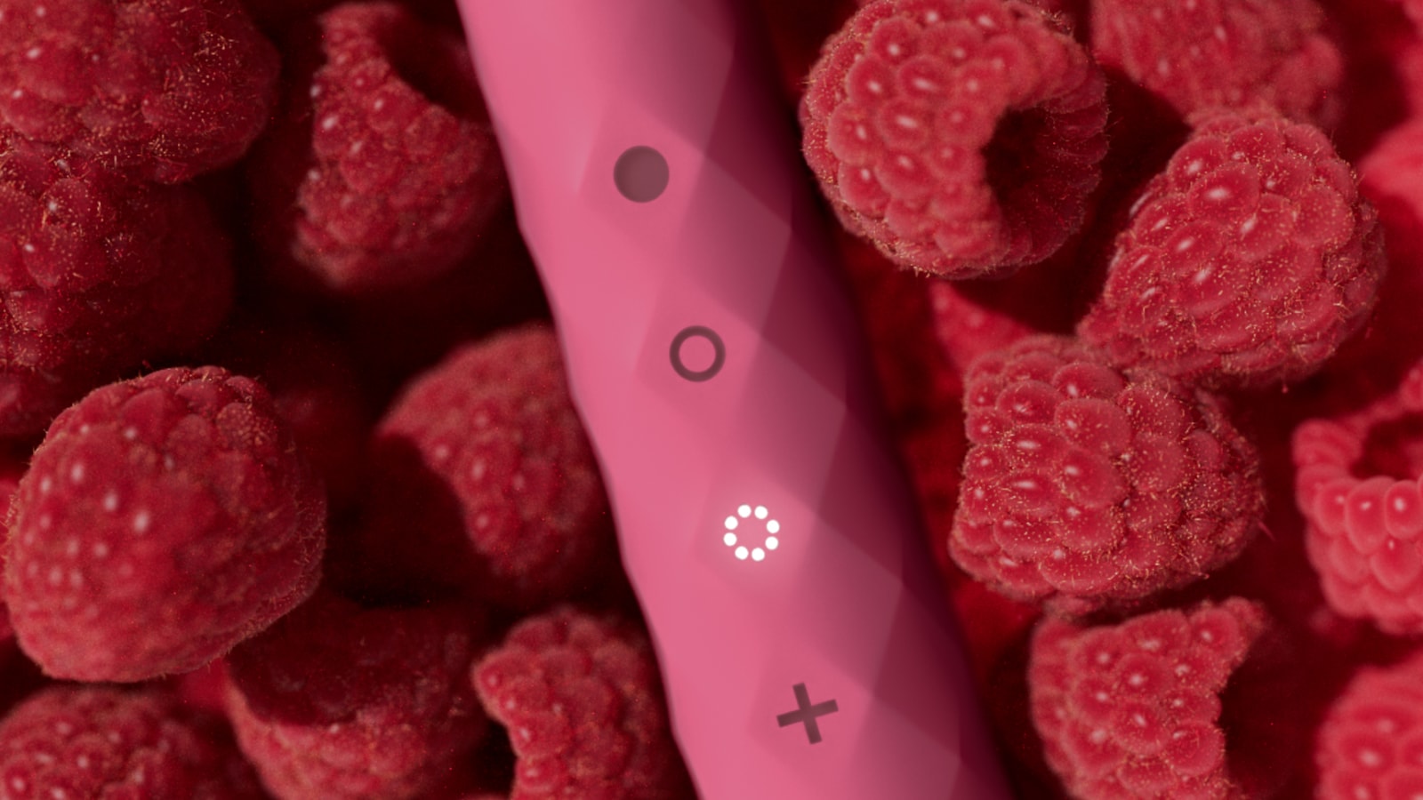 A pink Burst Berry toothbrush rests among raspberries.