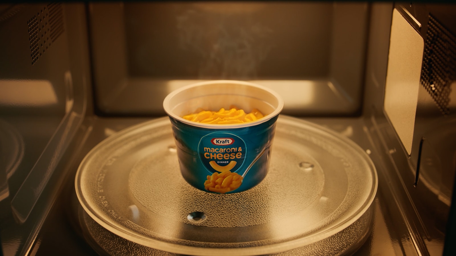 A steaming cup of Kraft macaroni and cheese in a microwave.