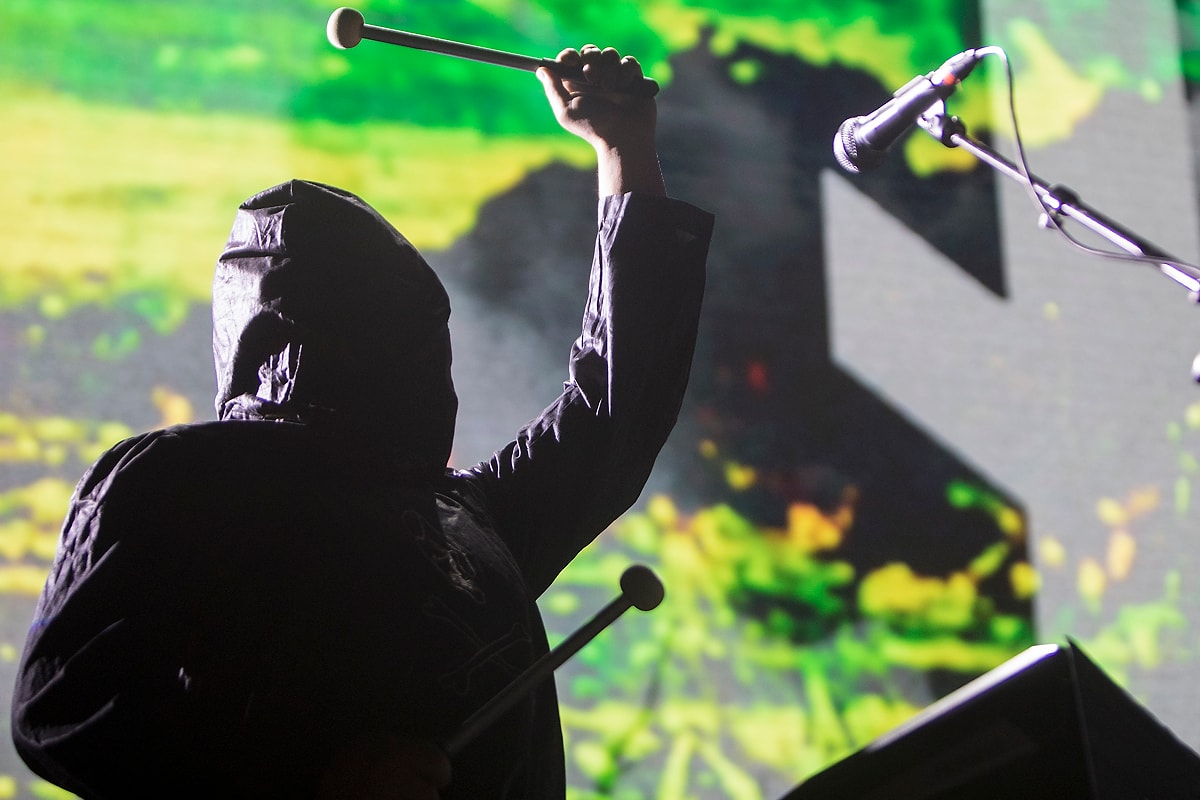 A singer raises a microphone in green stage light.