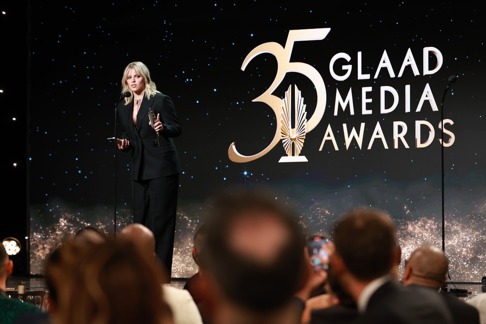 A speaker on stage against a dark backdrop with the 35th GLAAD Media Awards logo.