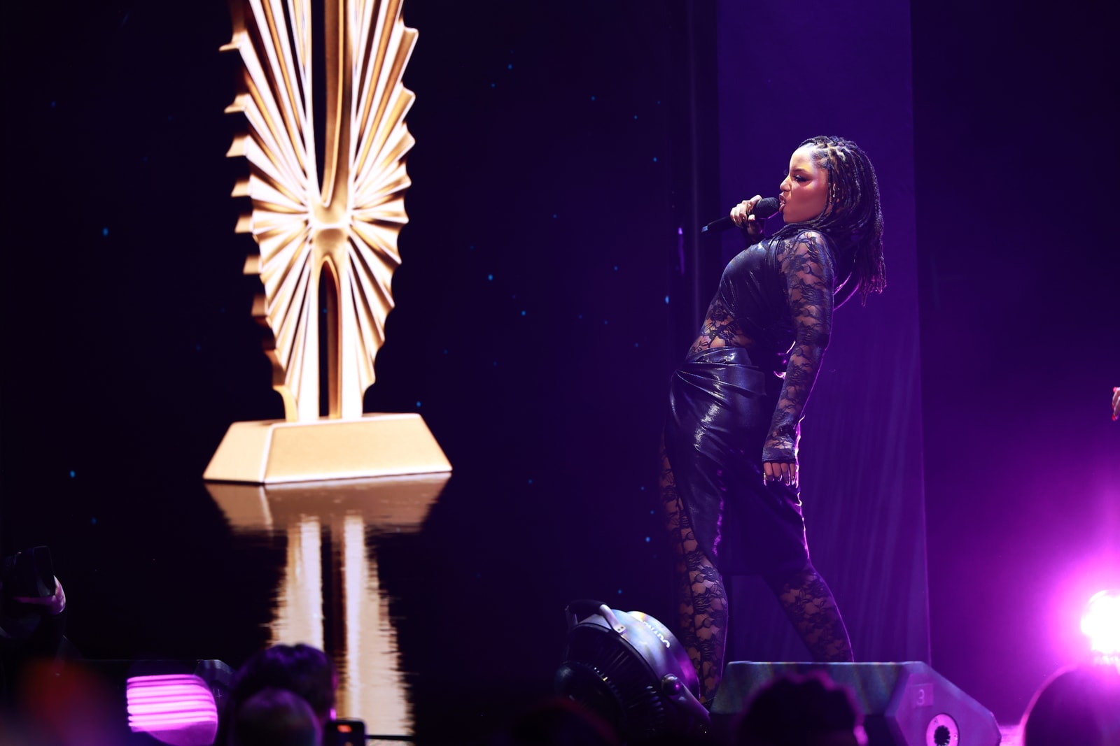 A performer stands beside a large gold GLAAD statuette screen graphic.