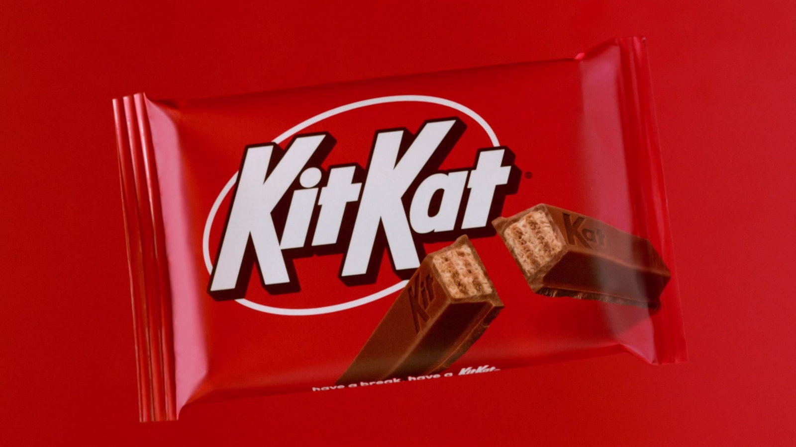 A red KitKat wrapper appears beside two chocolate fingers.