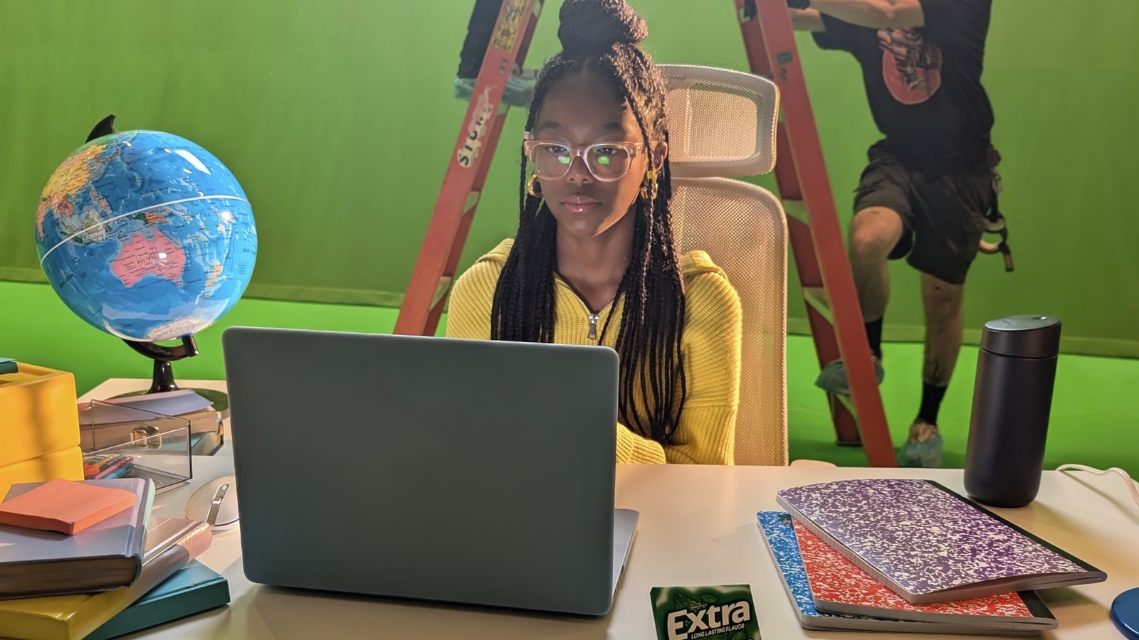 A performer at a desk on the Extra green-screen set.