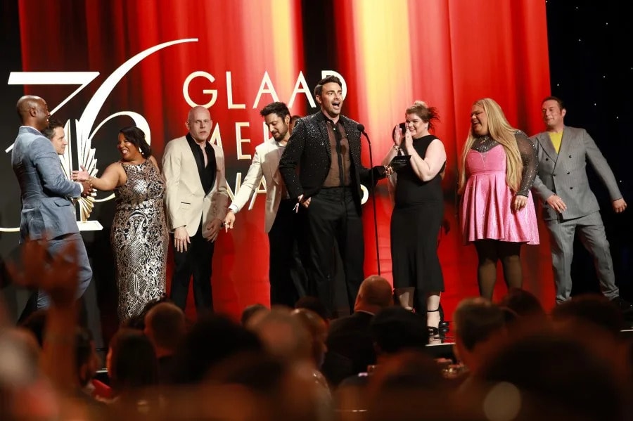 A group gathers on stage against red and gold 36th GLAAD Media Awards graphics.