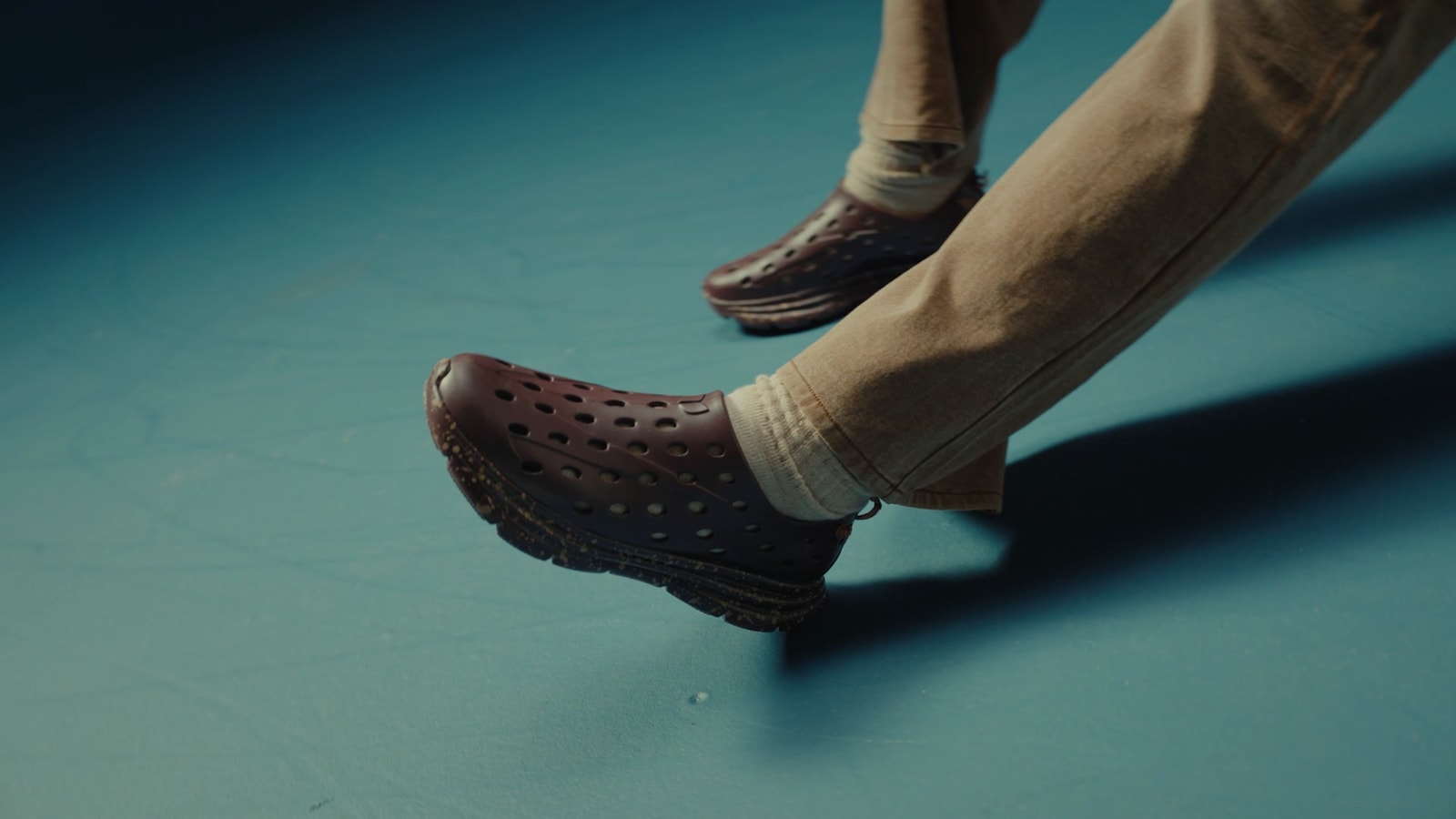 Close-up of Will Anderson Jr.’s brown KANE colorway with tan trousers against a blue studio floor.