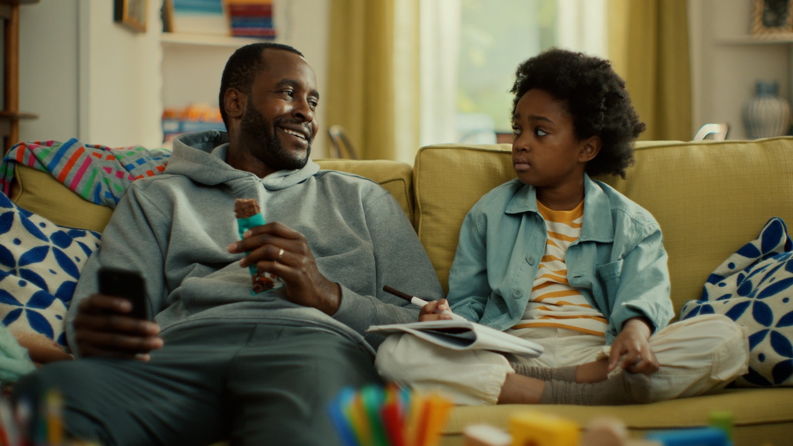 A father and child share a moment on the couch in a Fulfil spot.